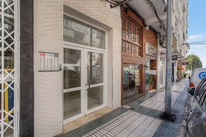 Ein Gebäude mit Glastür, einer Beschilderung mit Schrift und einem gefliesten Vorplatz.