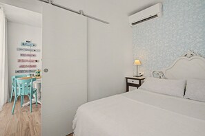 A bedroom with a bed, a nightstand, a lamp, a chair, and a wall with directional signs. - Apartment 'Playa Torrecilla' with Sea View, Wi-Fi and Air Conditioning (Nerja)
