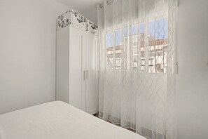 A bedroom with a bed, a wardrobe, and a window with a view of buildings. - Apartment 'Playa Torrecilla' with Sea View, Wi-Fi and Air Conditioning (Nerja)