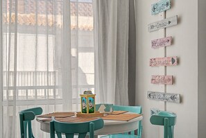A dining area with a round table, teal chairs, and a wall with directional signs. - Apartment 'Playa Torrecilla' with Sea View, Wi-Fi and Air Conditioning (Nerja)