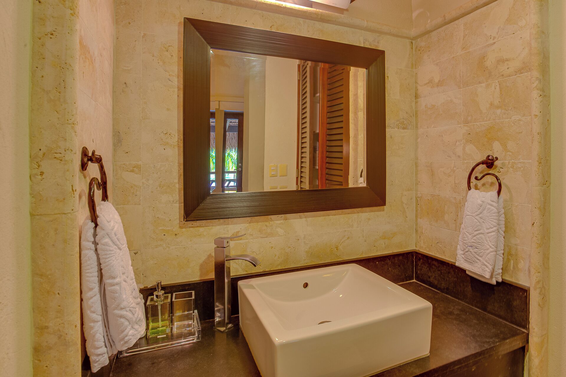 A bathroom with a large mirror, a white sink, and two towel hooks.