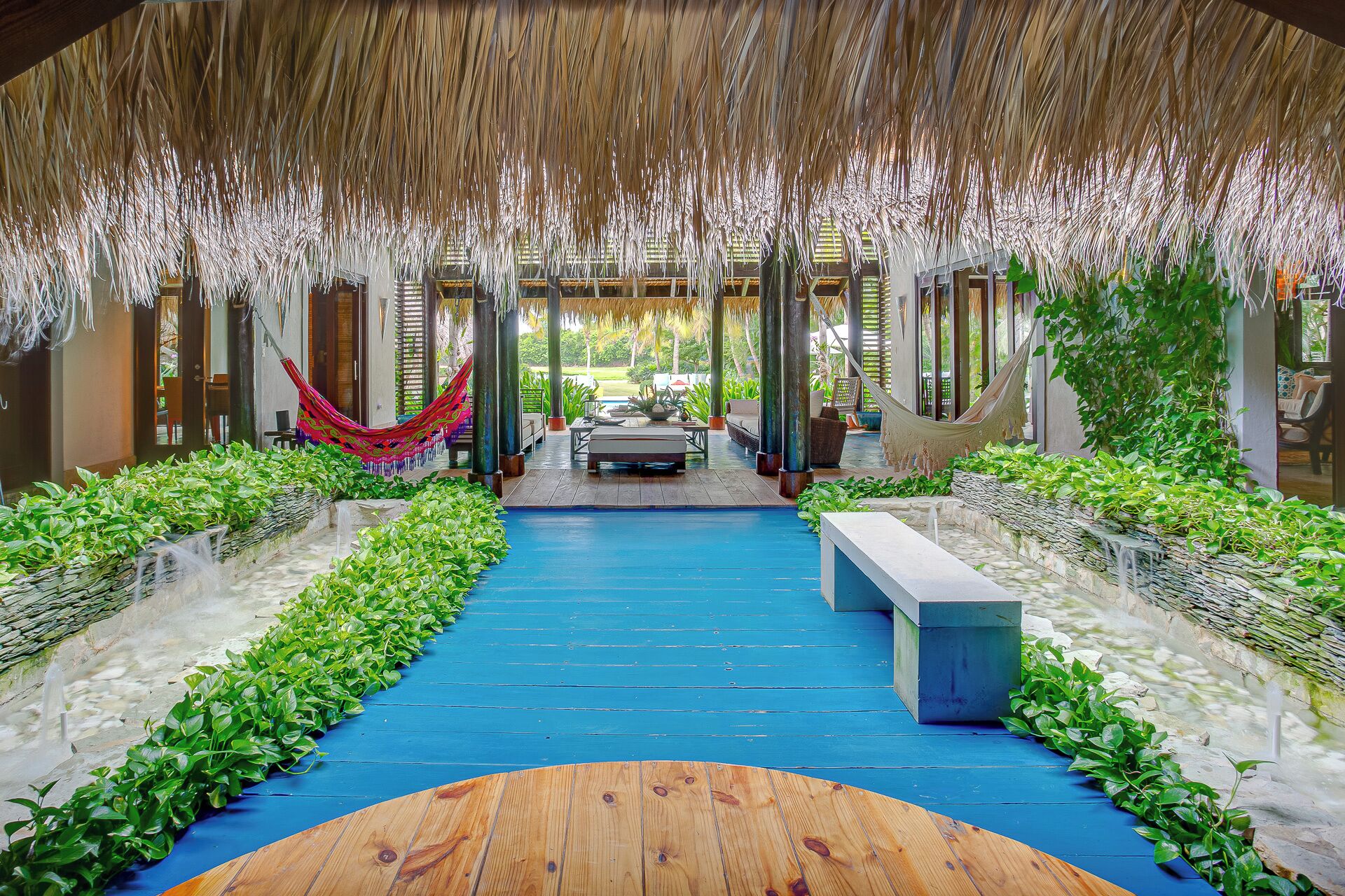 A covered outdoor area with a blue floor, benches, and a hammock.