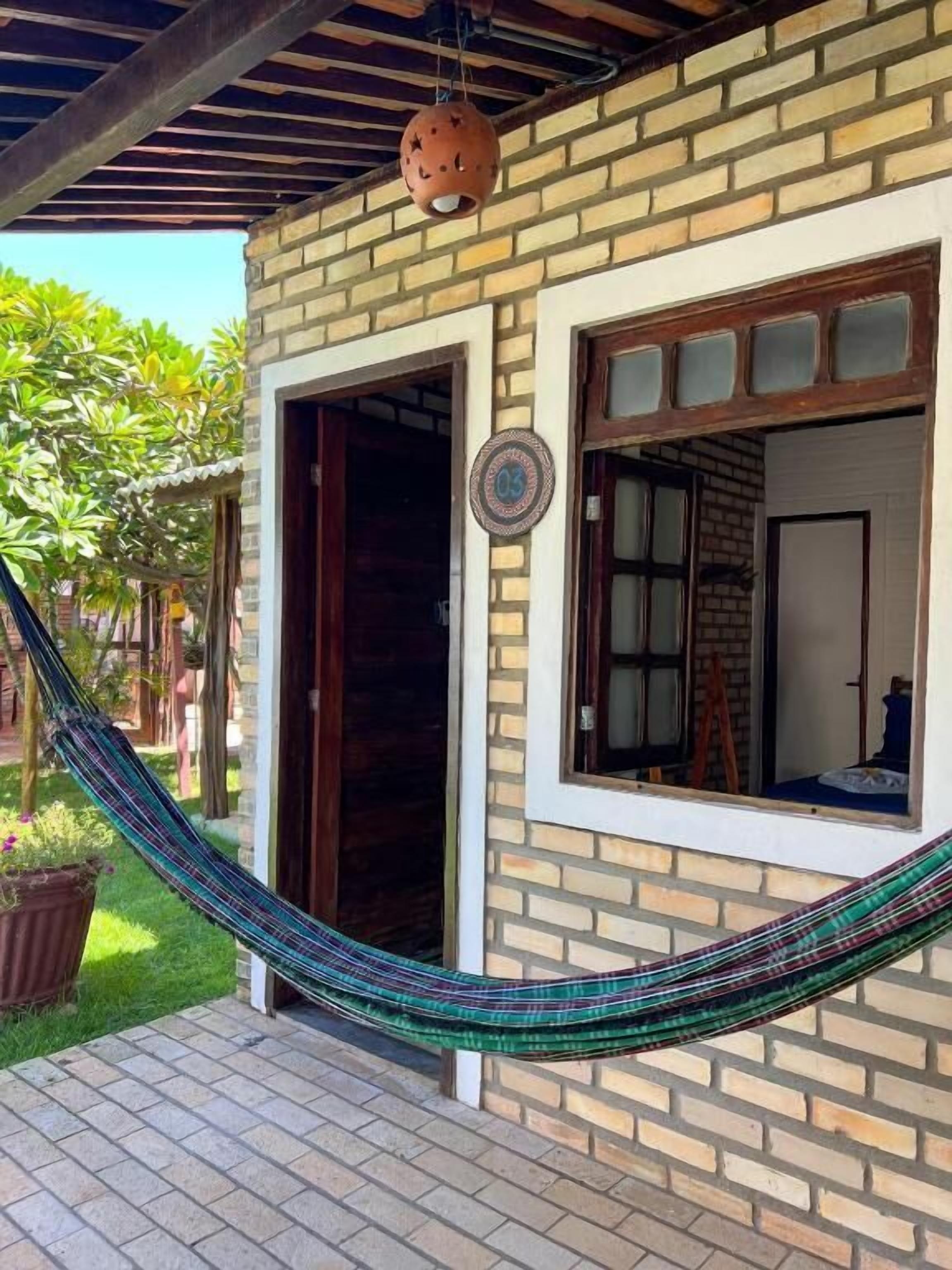 A brick building with a hammock, a door, and a window.