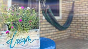 Un jardinier en bois avec des fleurs, posé sur une table bleue, devant un mur de briques et une fenêtre.