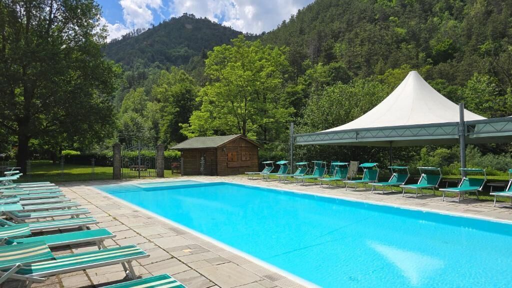 Una piscina con sdraio, una piccola cabina e una tenda.