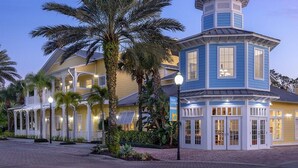 A hotel with a distinctive blue tower, a covered outdoor area, and palm trees. - 1 Bedroom Villa at Harbour Lake Family-Friendly (ORLANDO)