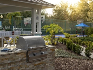 An outdoor grill area with a stone wall, a basketball hoop, and a blue umbrella. - 1 Bedroom Villa at Harbour Lake Family-Friendly (ORLANDO)