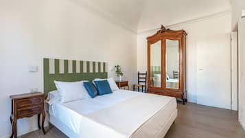 Un dormitorio con cama, mesita de noche, espejo y armario.
