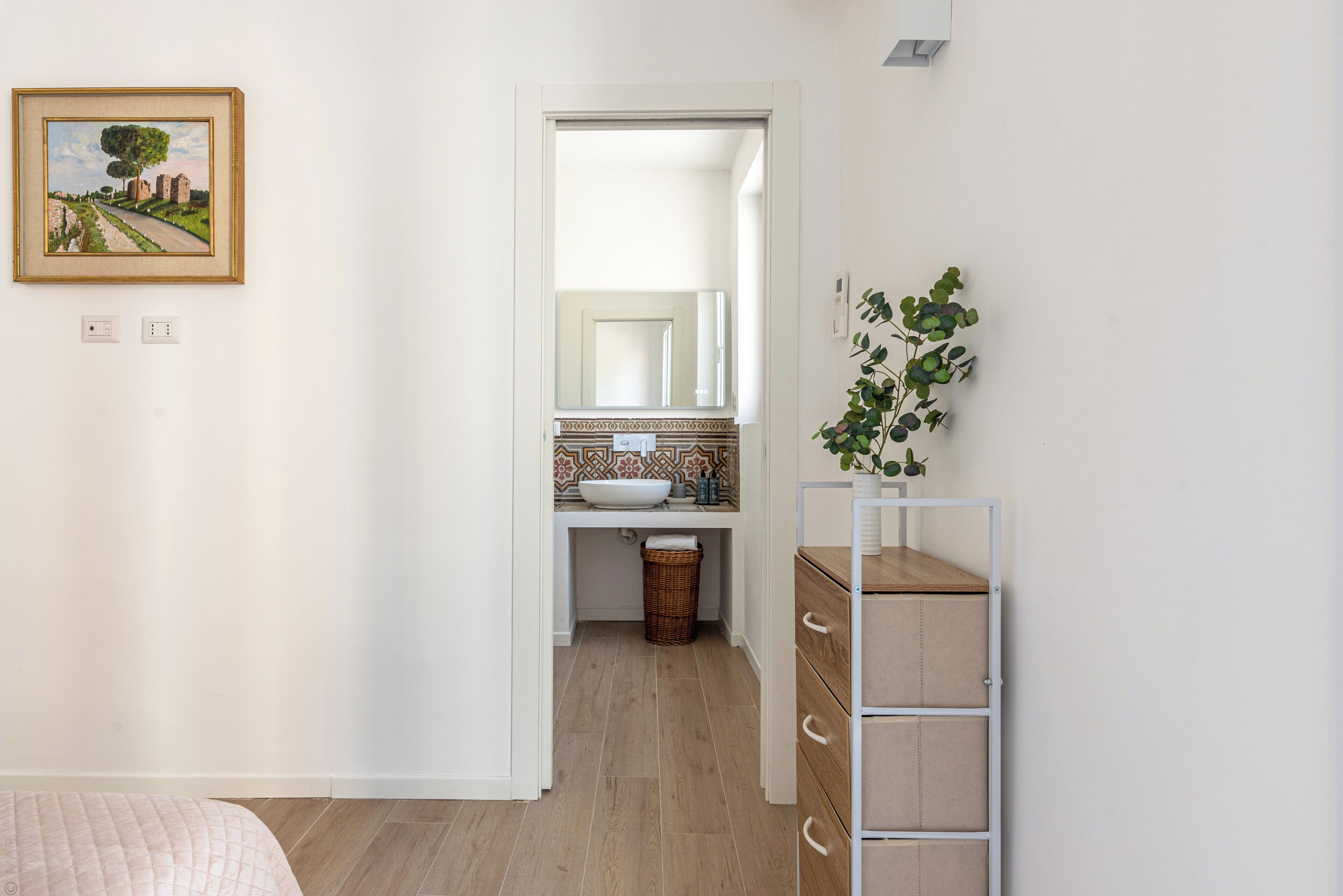 Un dormitorio con cama, cómoda, espejo y un cuadro en la pared.