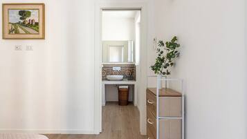 Un dormitorio con cama, cómoda, espejo y un cuadro en la pared.