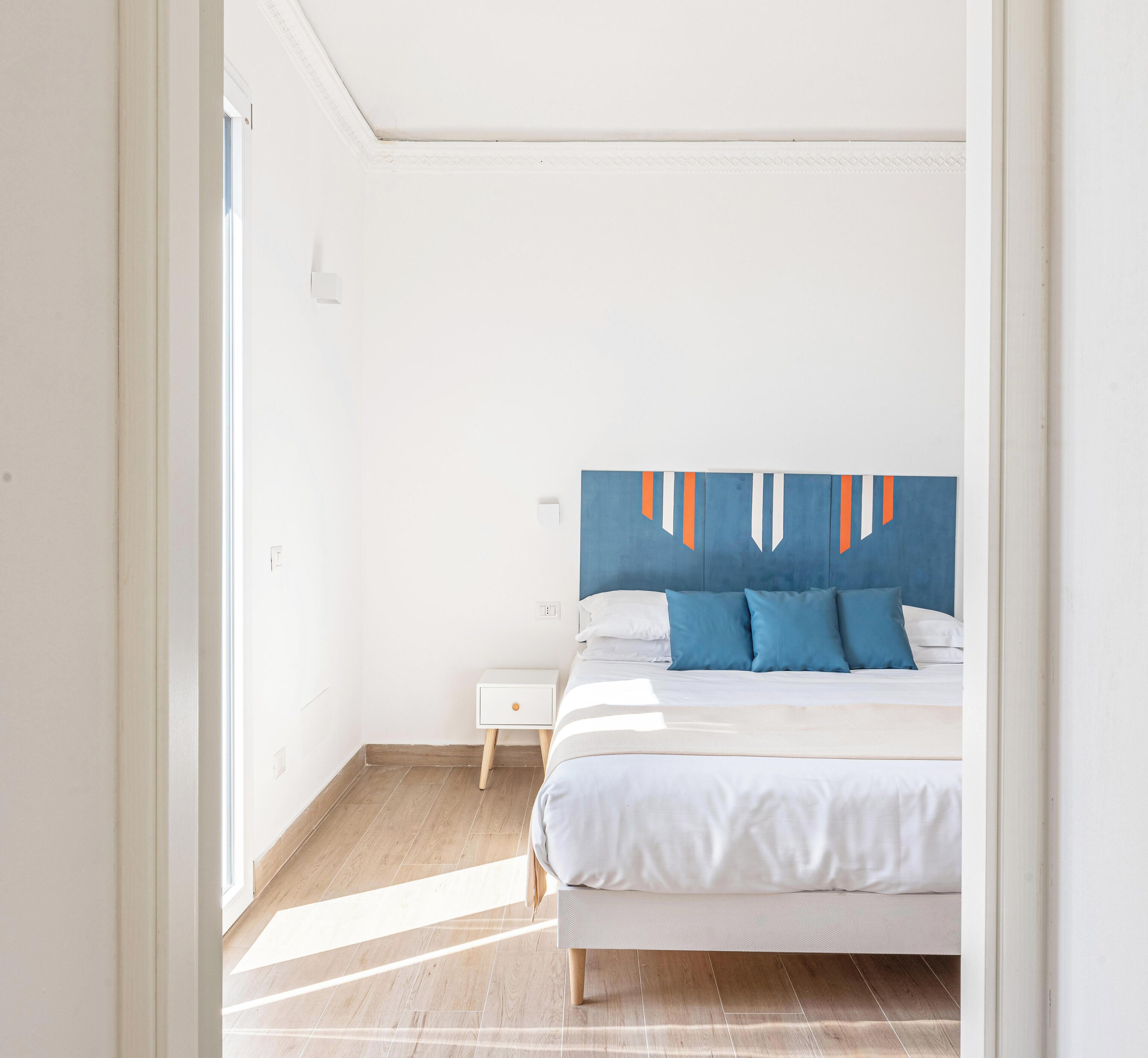 Une chambre à coucher avec un lit, une table de chevet et une œuvre d’art murale.