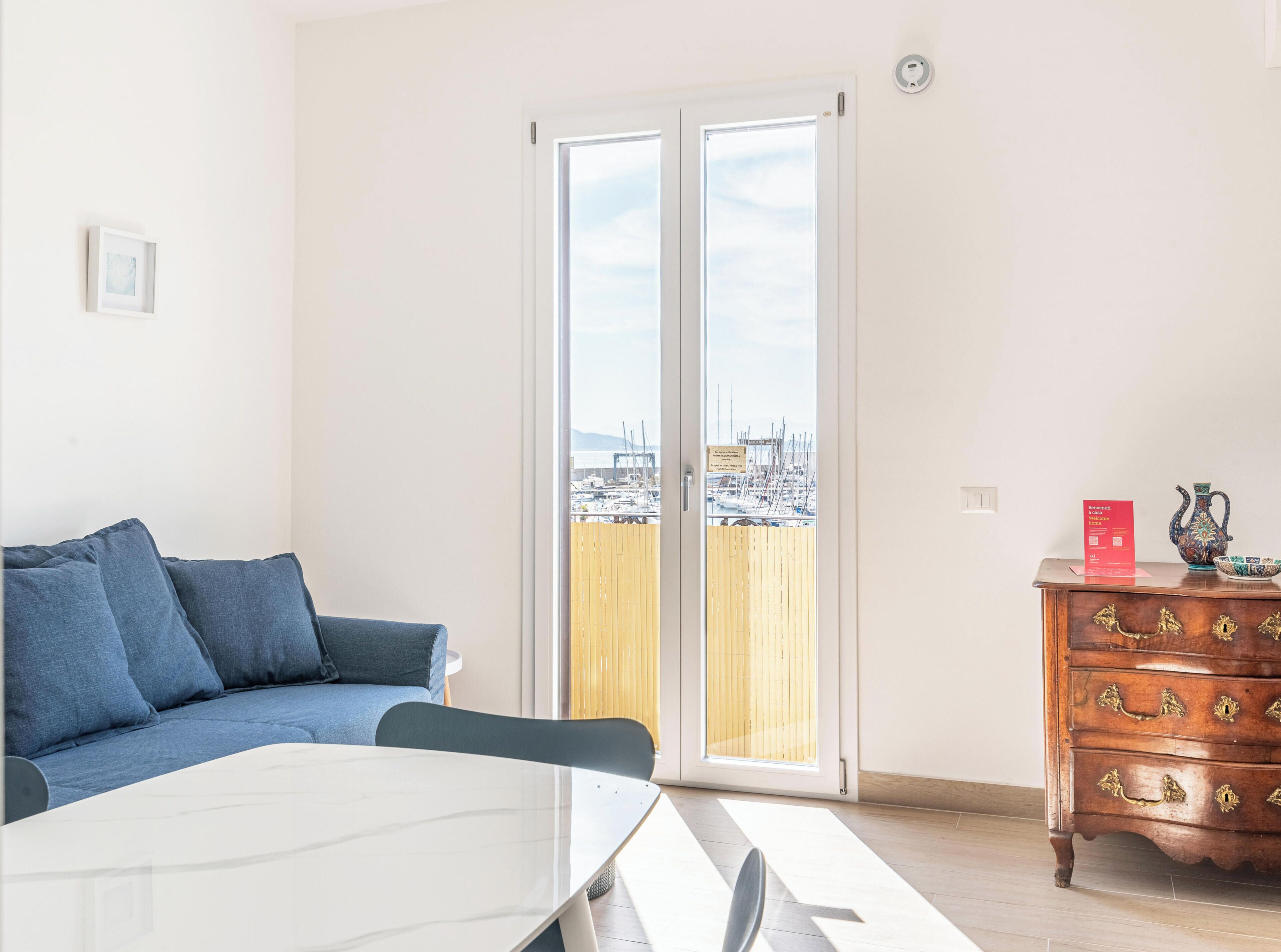 Una habitación con un sofá, una mesa de comedor y un aparador de madera con cajones.