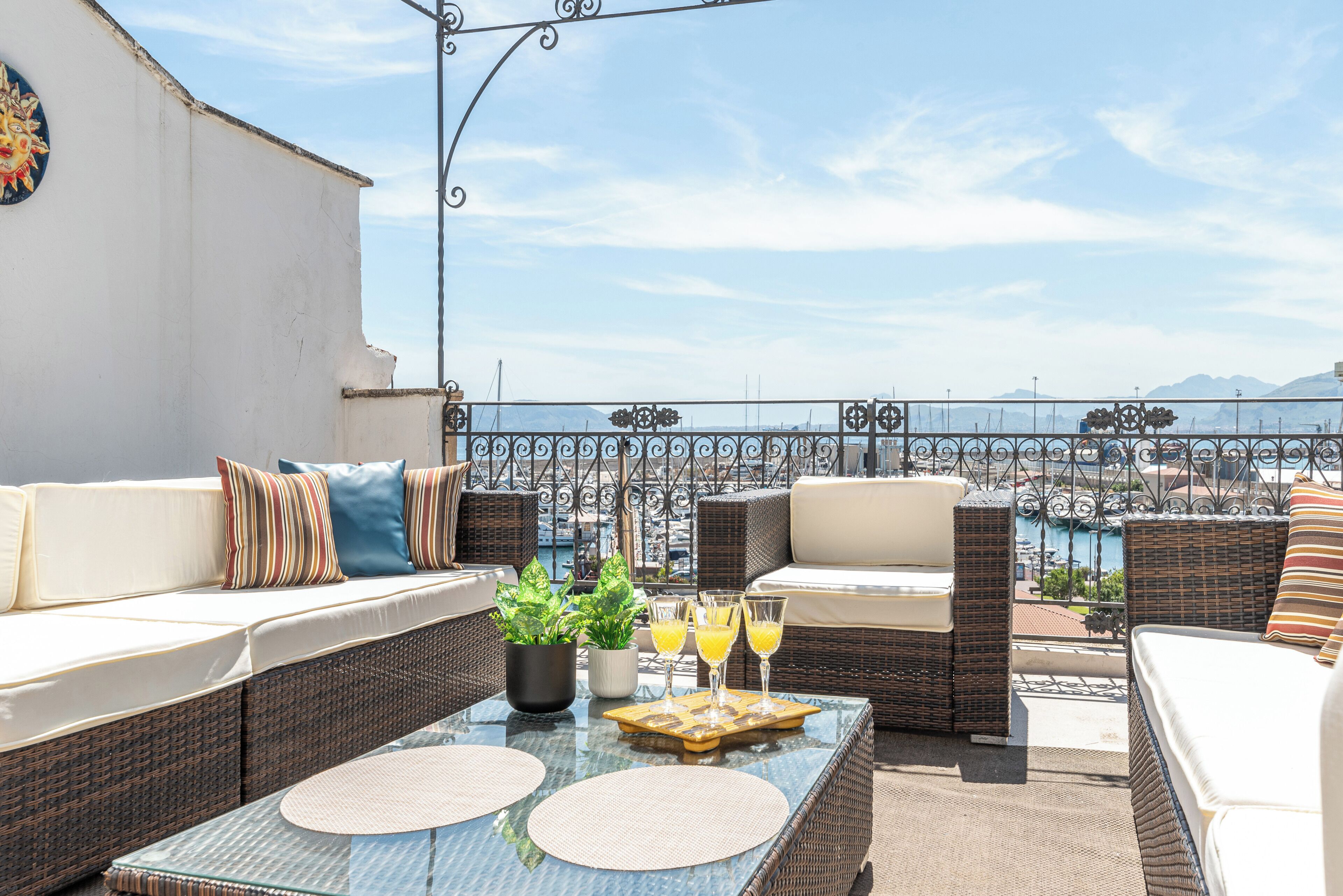 Ein Balkon mit Korbmöbeln, einem Tisch mit Getränken und Blick auf den Yachthafen.