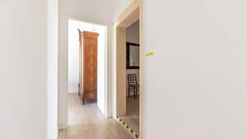 Un pasillo con una puerta de madera, un cartel de precaución y una silla.