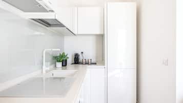 Una cocina moderna con muebles blancos, estufa empotrada y un lavamanos.