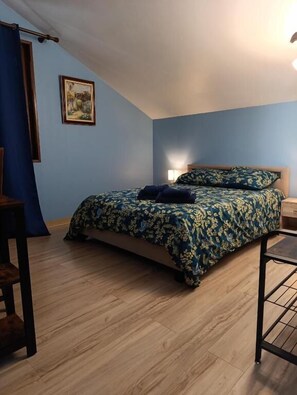 Ein Schlafzimmer mit Bett, Schreibtisch, Stuhl, Lampe und einem Bild an der Wand.