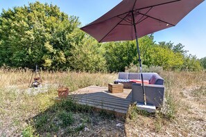 Un espacio de estar al aire libre con terraza de madera, sofá y sombrilla.