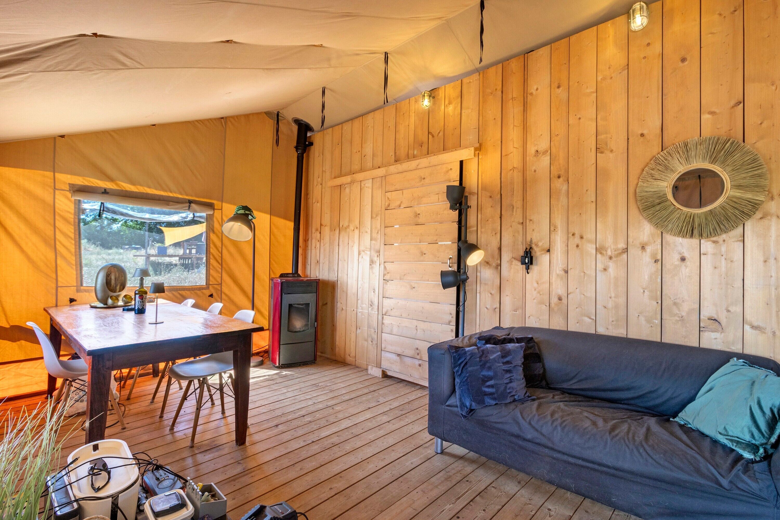 A cozy interior with a wooden floor, a dining table with chairs, a sofa, and a wall-mounted heater.