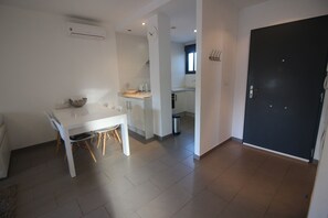 A modern kitchen with white cabinets, a dining table with chairs, and a black door. - Groundfloor Oasis Beach II La Zenia (Orihuela)