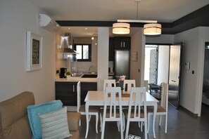 Eine moderne Küche mit Essbereich, inklusive einer zentralen Kochinsel, weißen Stühlen und Pendelleuchten.