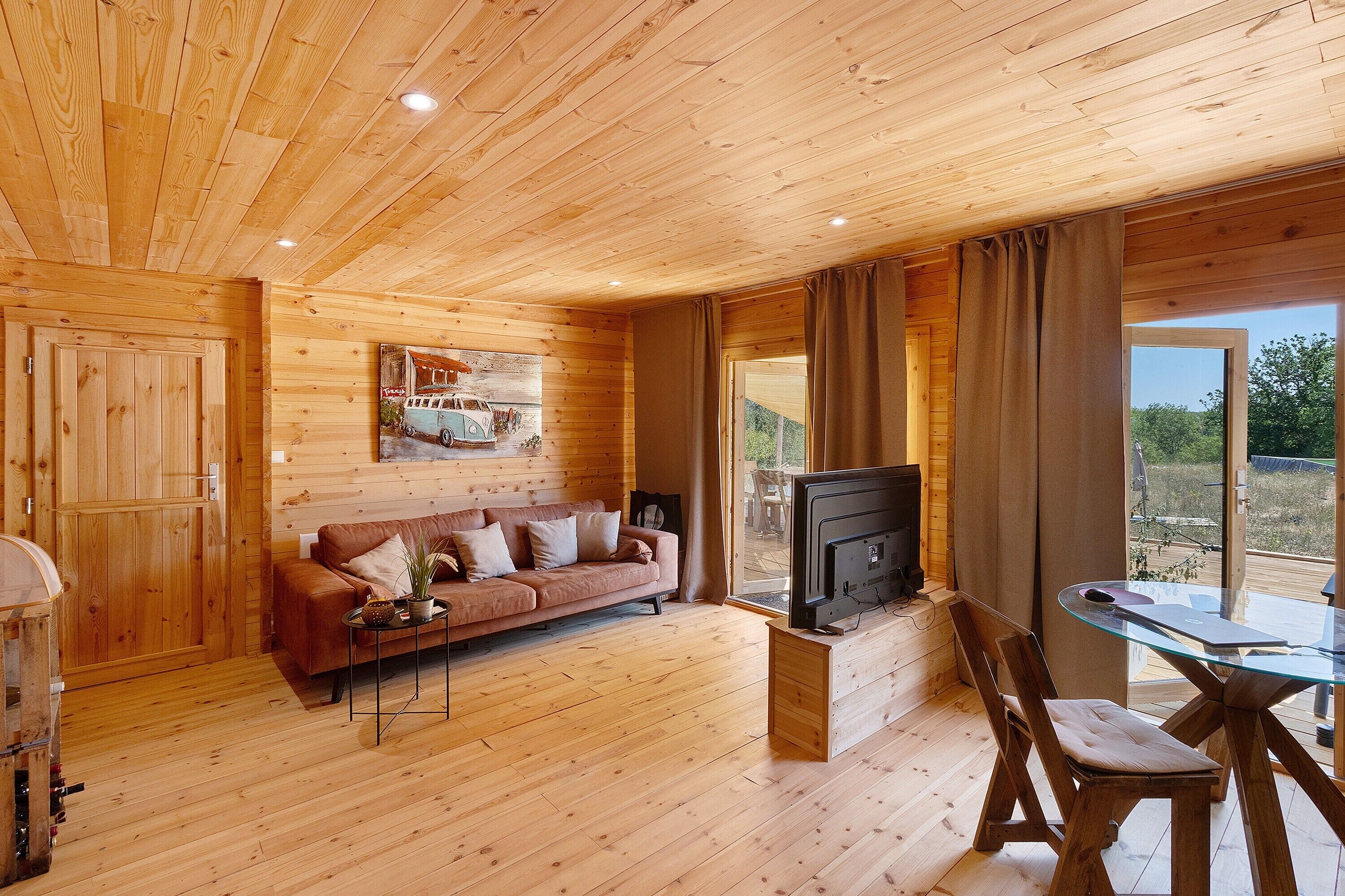 Ein Holzinterieur mit einer Couch, einem Fernseher und einem Essbereich.