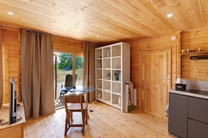 A wooden interior with a dining table, a white shelving unit, and a kitchen area. - Holiday Home 'Aurélie' with Wi-Fi (Lavalade)