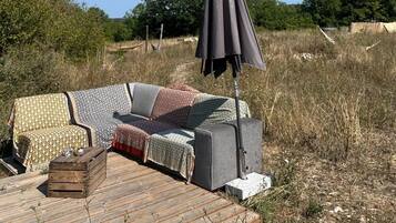 An outdoor seating area with a sofa and a table, an umbrella, and a view of the surrounding landscape.