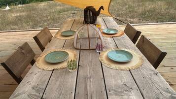 A wooden dining table with woven placemats, plates, and a glass.