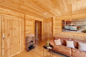 A wooden interior with a sofa, a painting of a vintage car, and a wine rack. - Holiday Home 'Aurélie' with Wi-Fi (Lavalade)