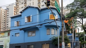 A multi-story building with a blue facade, a stone base, and multiple windows.