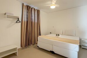 Un dormitorio con cama, ventilador de techo, mesita de noche y armario.