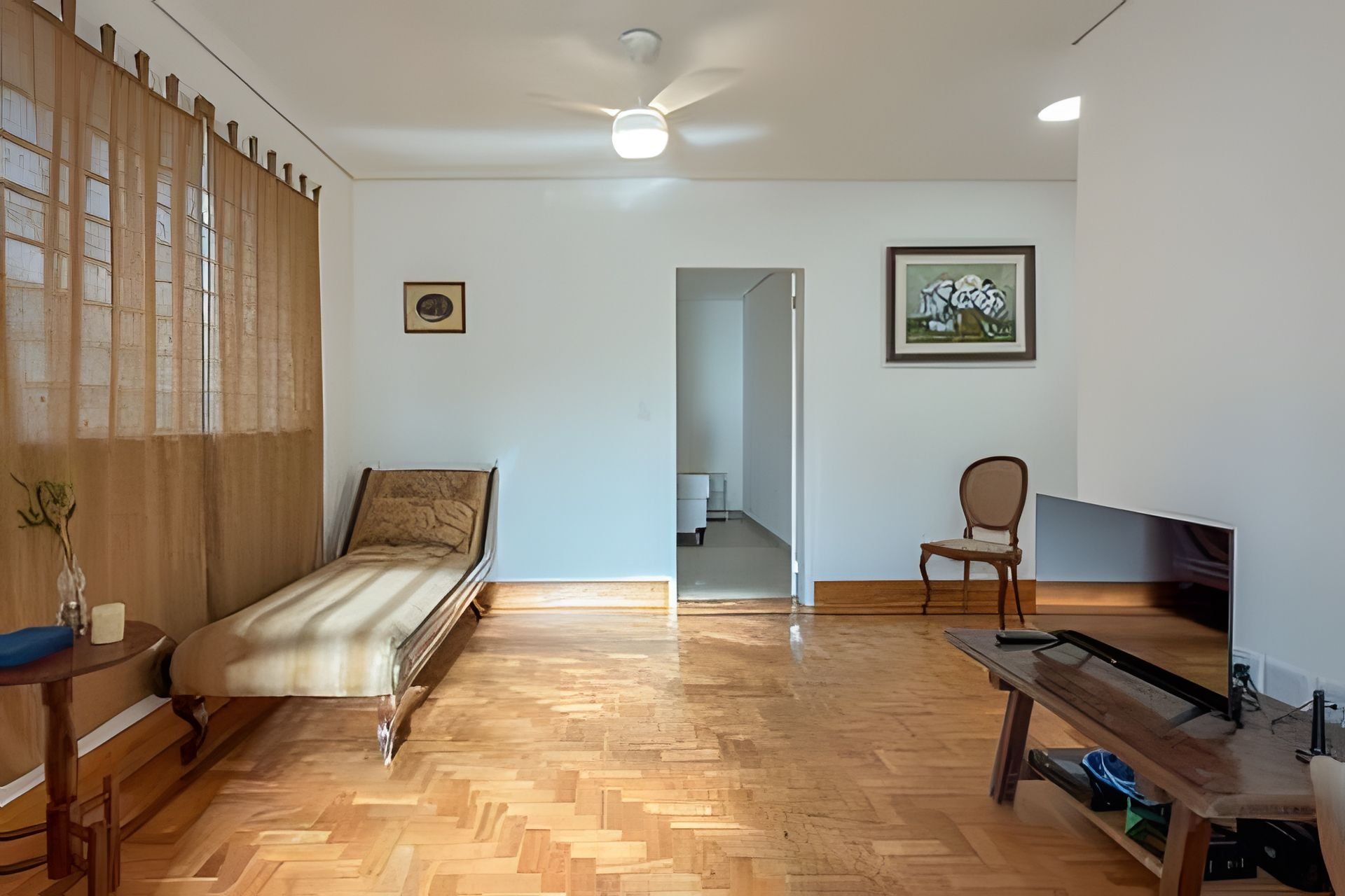 A room with a bed, a desk, a chair, a television, and a ceiling fan.