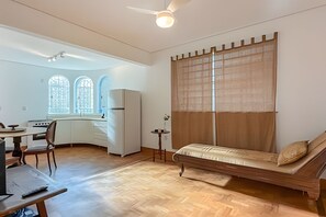 A compact living space with a kitchenette, a dining area, and a large window with a view. - Aconchego Cotoxó - Loft 2 (São Paulo)