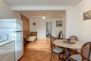 A compact living space with a kitchenette, a bed, a dining table with chairs, and a ceiling fan. - Aconchego Cotoxó - Loft 2 (São Paulo)