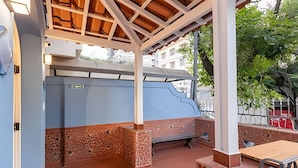 An outdoor patio with a covered seating area, a brick wall, and a wooden table.