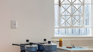A kitchen with a white stove, oven, and a window with a white grid design.