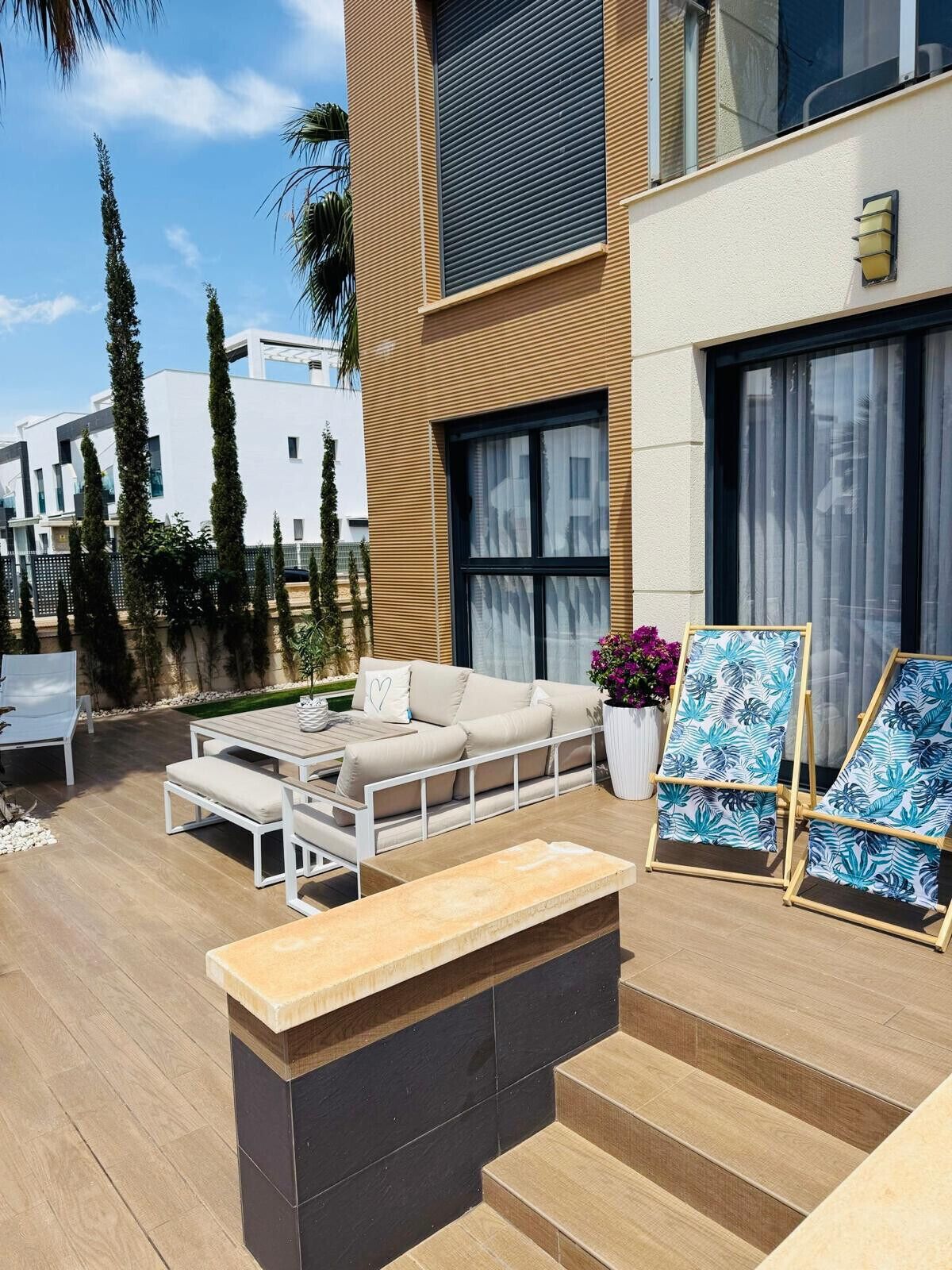 A modern outdoor patio with a sofa, coffee table, and lounge chairs.