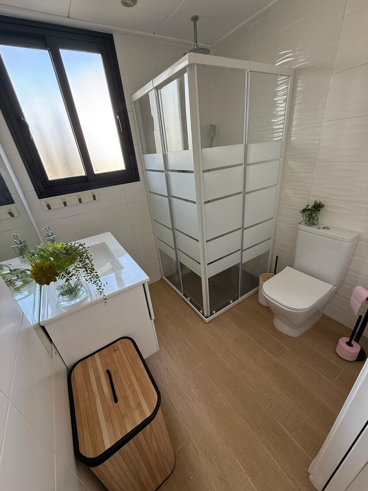 A modern bathroom with a shower enclosure, toilet, and sink area.