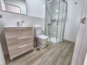 A modern bathroom with a wooden vanity, a toilet, and a glass shower enclosure. - House in Gran Canaria Near Playa de Las Canteras (Las Palmas de Gran Canaria)