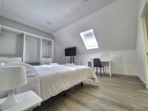 A modern bedroom with a bed, bedside table, wardrobe, desk, and a skylight. - House in Gran Canaria Near Playa de Las Canteras (Las Palmas de Gran Canaria)