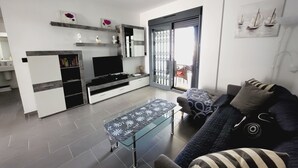 Een moderne woonkamer met een televisie, bank en salontafel.