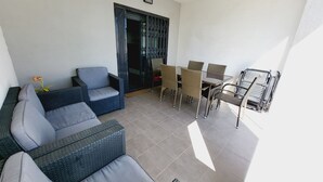 Een balkon met een bank, stoelen en een tafel.