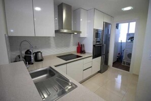 Eine moderne Küche mit Edelstahlgeräten, weißen Schränken und einem eingebauten Backofen.