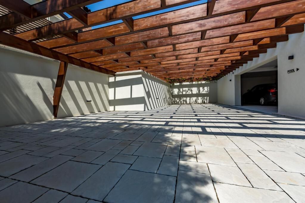 A covered outdoor area with a tiled floor, wooden beams overhead, and a sign indicating a pool.