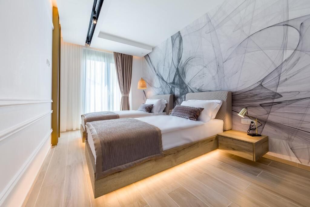A modern bedroom with a large bed, bedside tables, and a wall art piece.