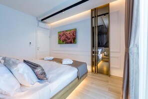 A hotel room with a bed, a painting, a wardrobe, and a mirror.