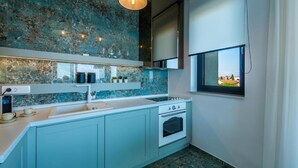 A modern kitchen with a blue marble backsplash, white cabinets, and a built-in oven. - Rocca Riviera  (Umag)