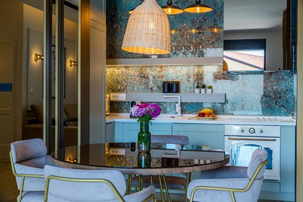 Una cucina moderna con un tavolo rotondo in vetro, due sedie e un vaso di fiori.