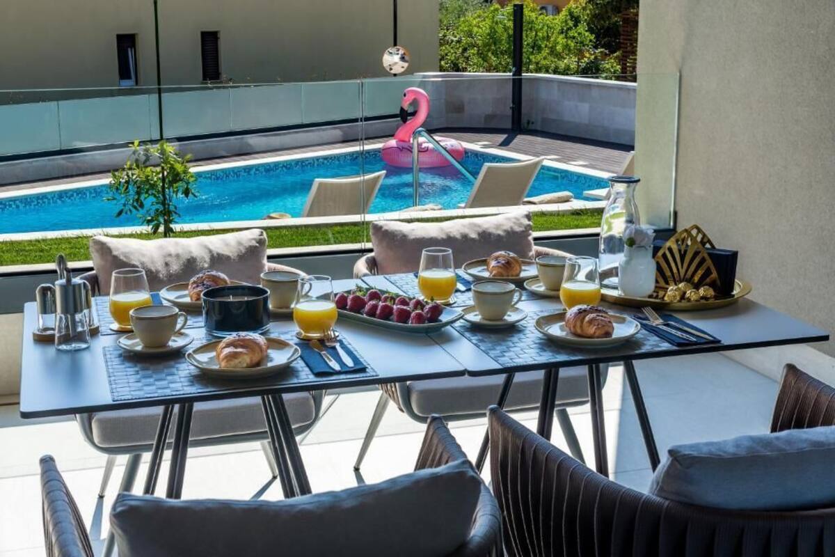 A breakfast setup with a table, chairs, and a pool with a flamingo float.