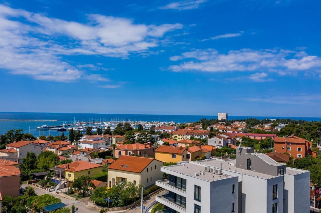 A coastal town with a marina, residential buildings, and a clear blue sky.